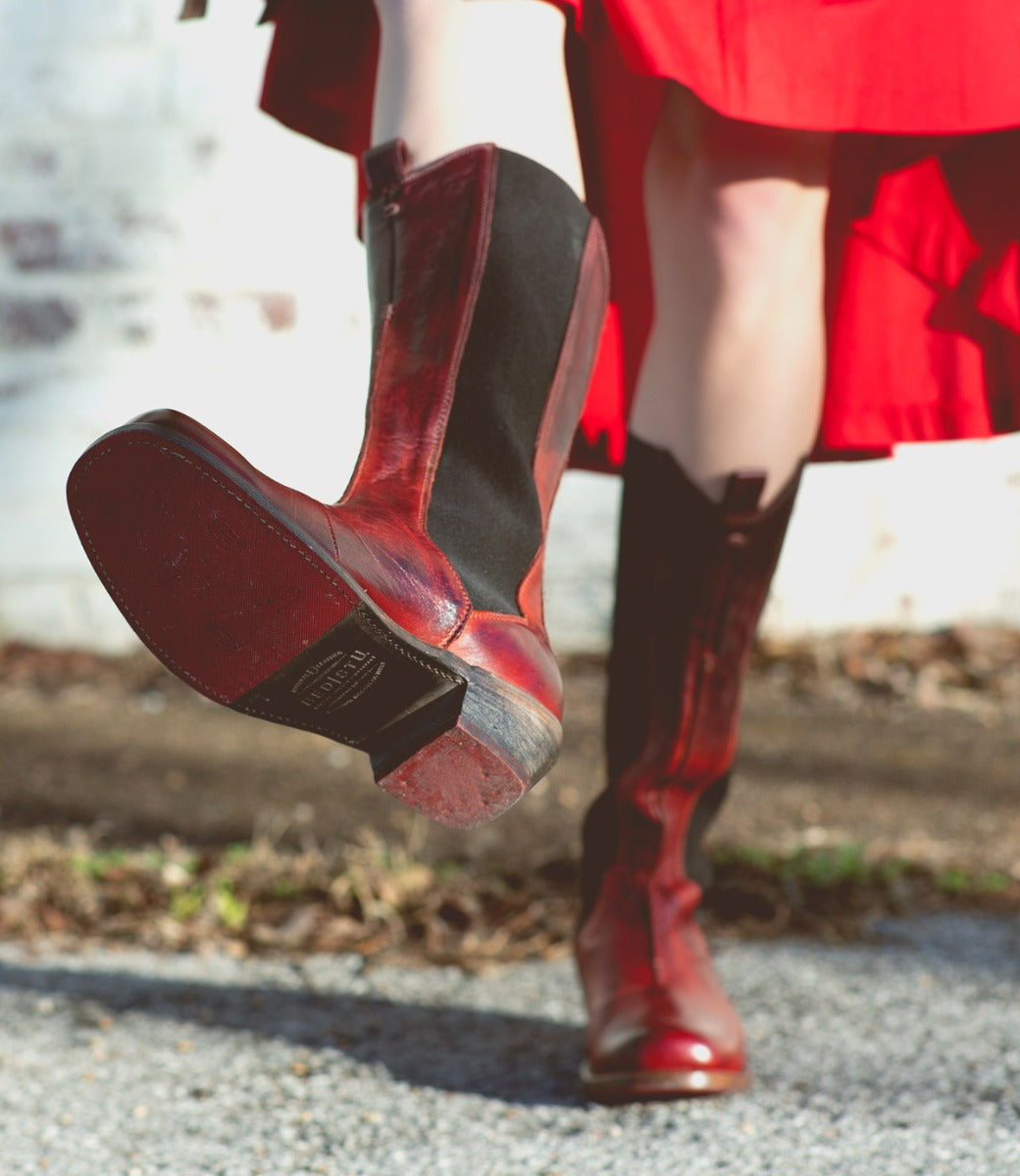 A woman wearing a red dress and Clarisse boots by  Bed Stu.