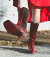 A woman wearing a red dress and Clarisse boots by  Bed Stu.