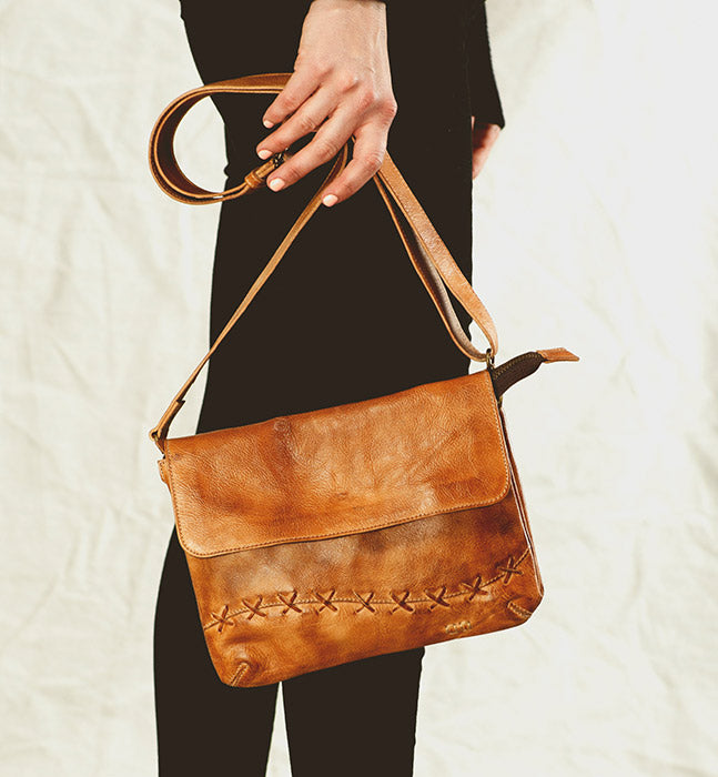 A woman holding a brown leather Bed Stu Cleo crossbody bag.
