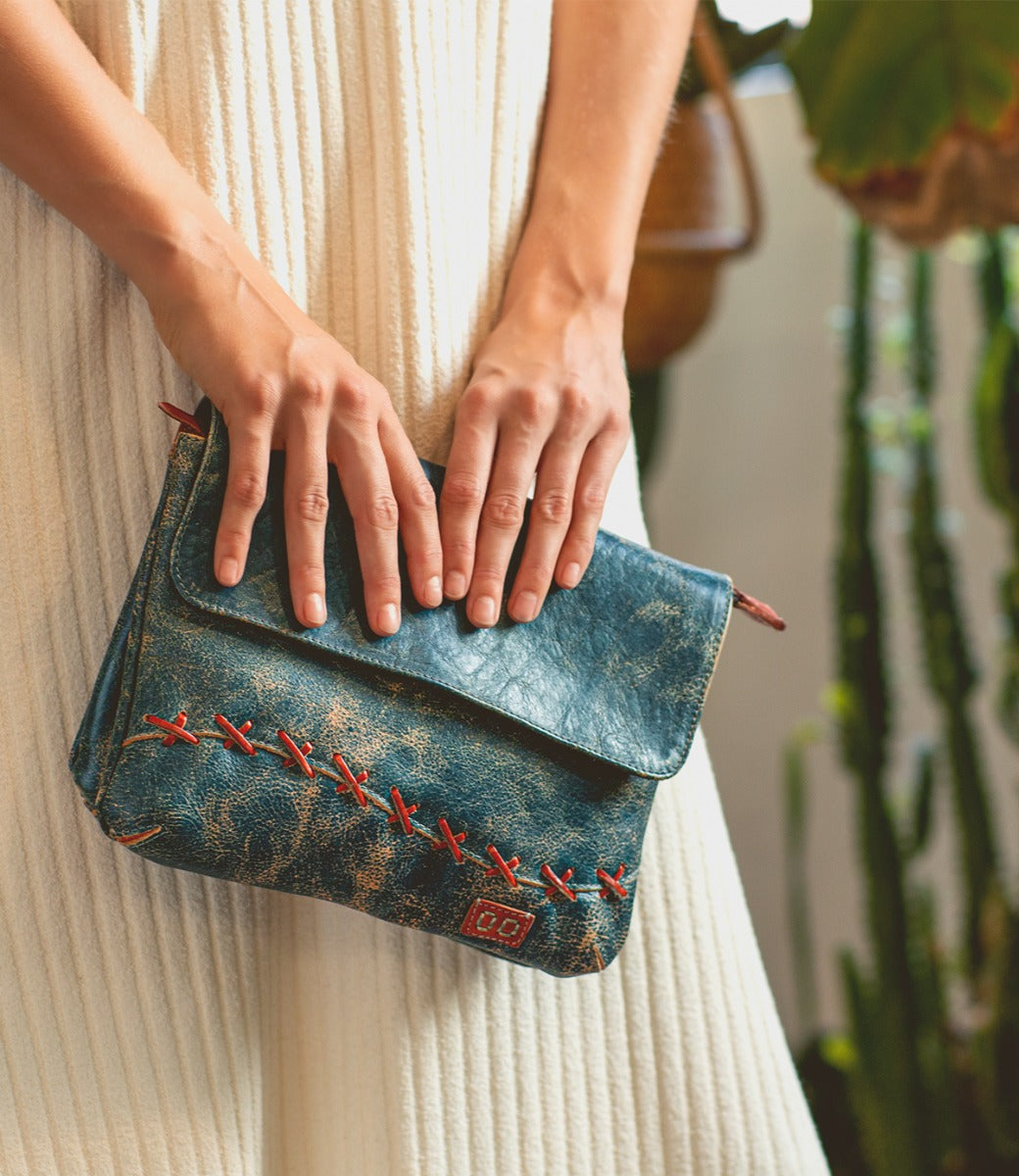 A woman holding a blue and red Bed Stu Cleo leather bag.