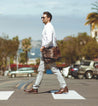 A man crossing a street with a Bed Stu Clyde bag.