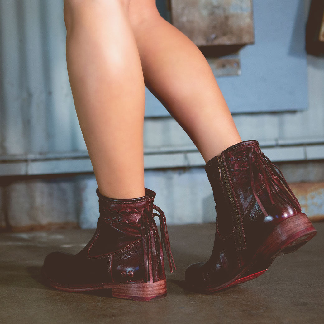 A woman in Bed Stu Craven burgundy leather boots.
