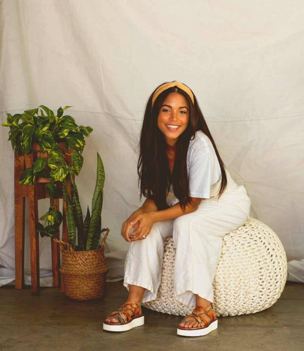 A woman sitting on a white Bed Stu Crawler with a potted plant.