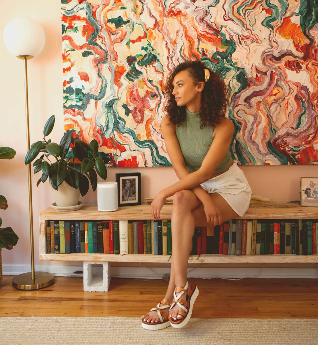 A Bed Stu Crawler sitting on a shelf in front of a colorful painting.