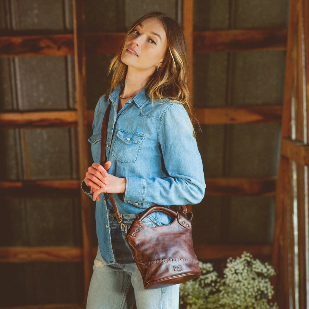 A woman wearing jeans and a Bed Stu Delilah leather purse.