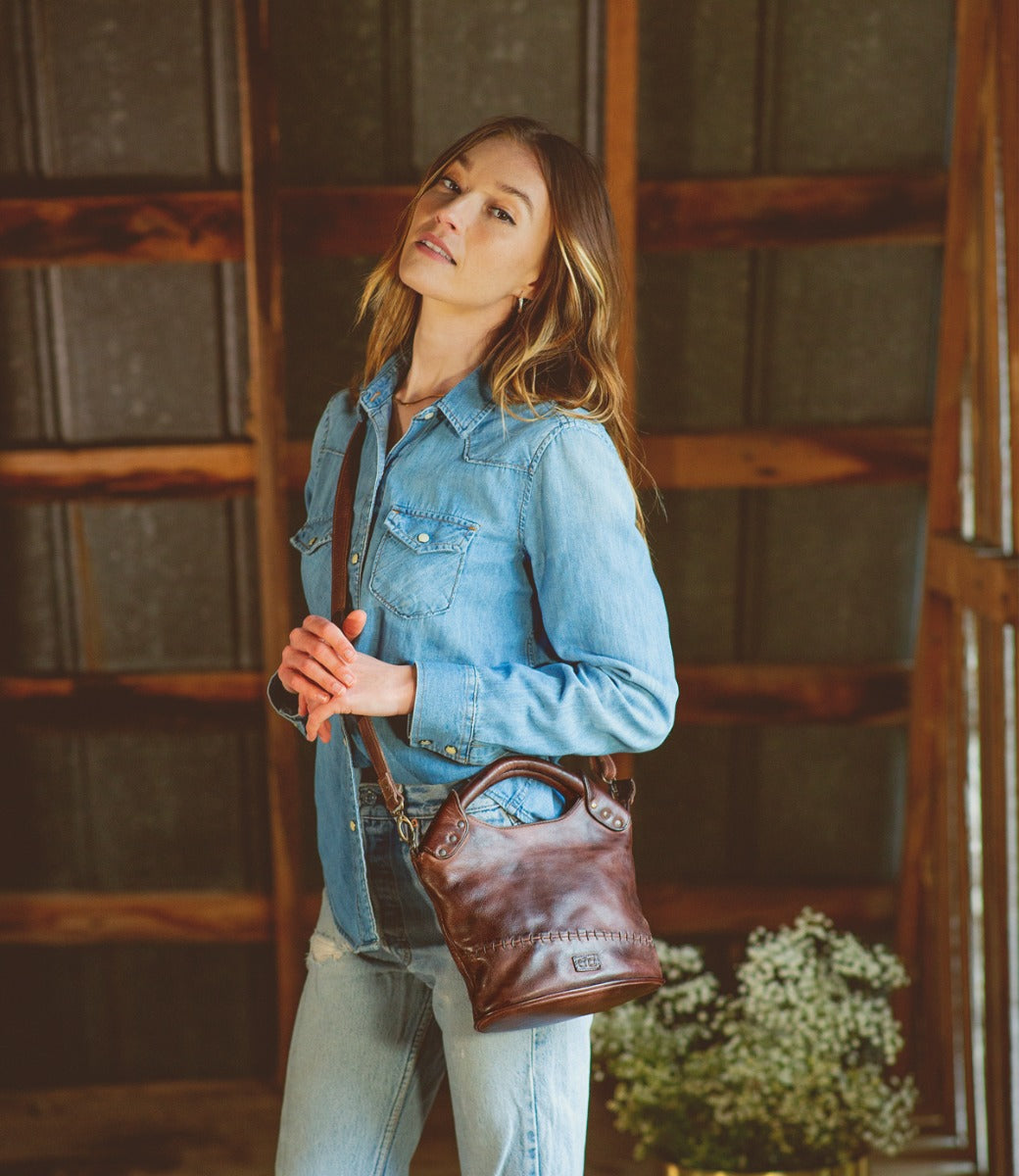 A woman wearing jeans and a Bed Stu Delilah leather purse.