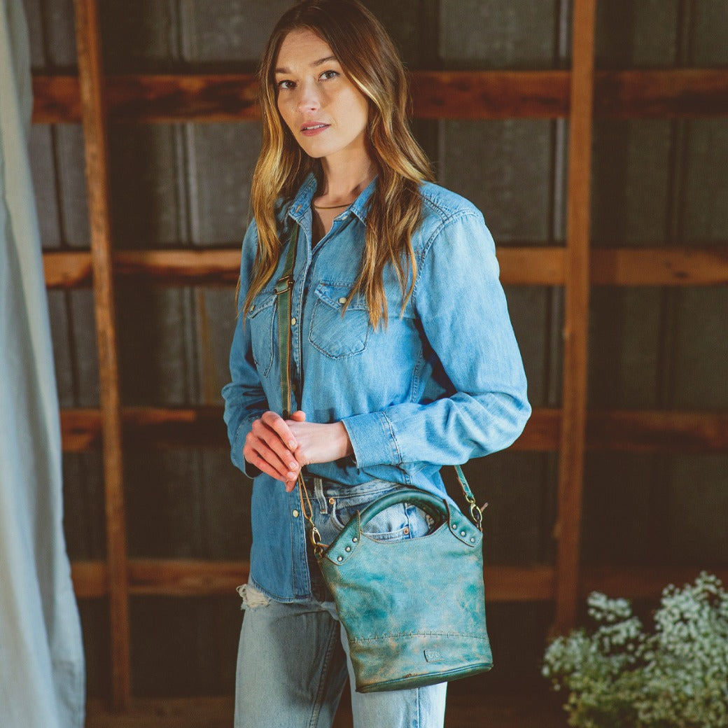A woman wearing jeans and a blue Bed Stu Delilah purse.