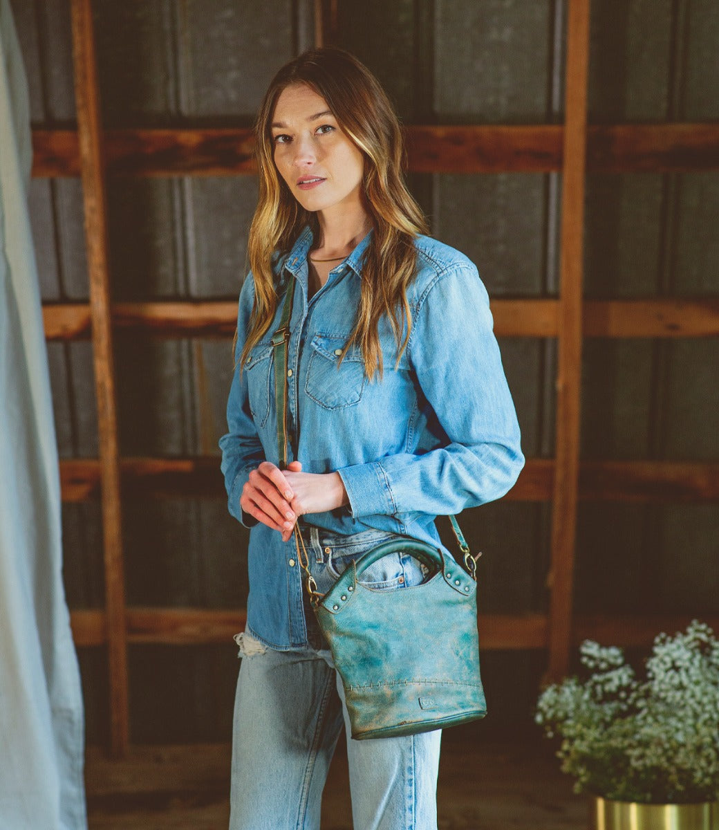 A woman wearing jeans and a blue Bed Stu Delilah purse.