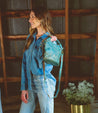 A woman wearing Delilah denim jeans and a Bed Stu turquoise purse.