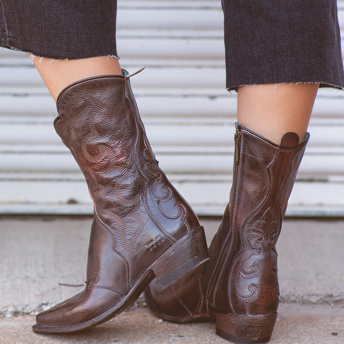 A woman sporting a pair of Bed Stu Deuce western-style cowboy leather boots.