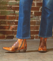 A woman exuding rustic charm in her Bed Stu Deuce jeans and leather cowboy boots.