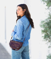 A woman wearing a Dolon by Bed Stu burgundy leather purse.