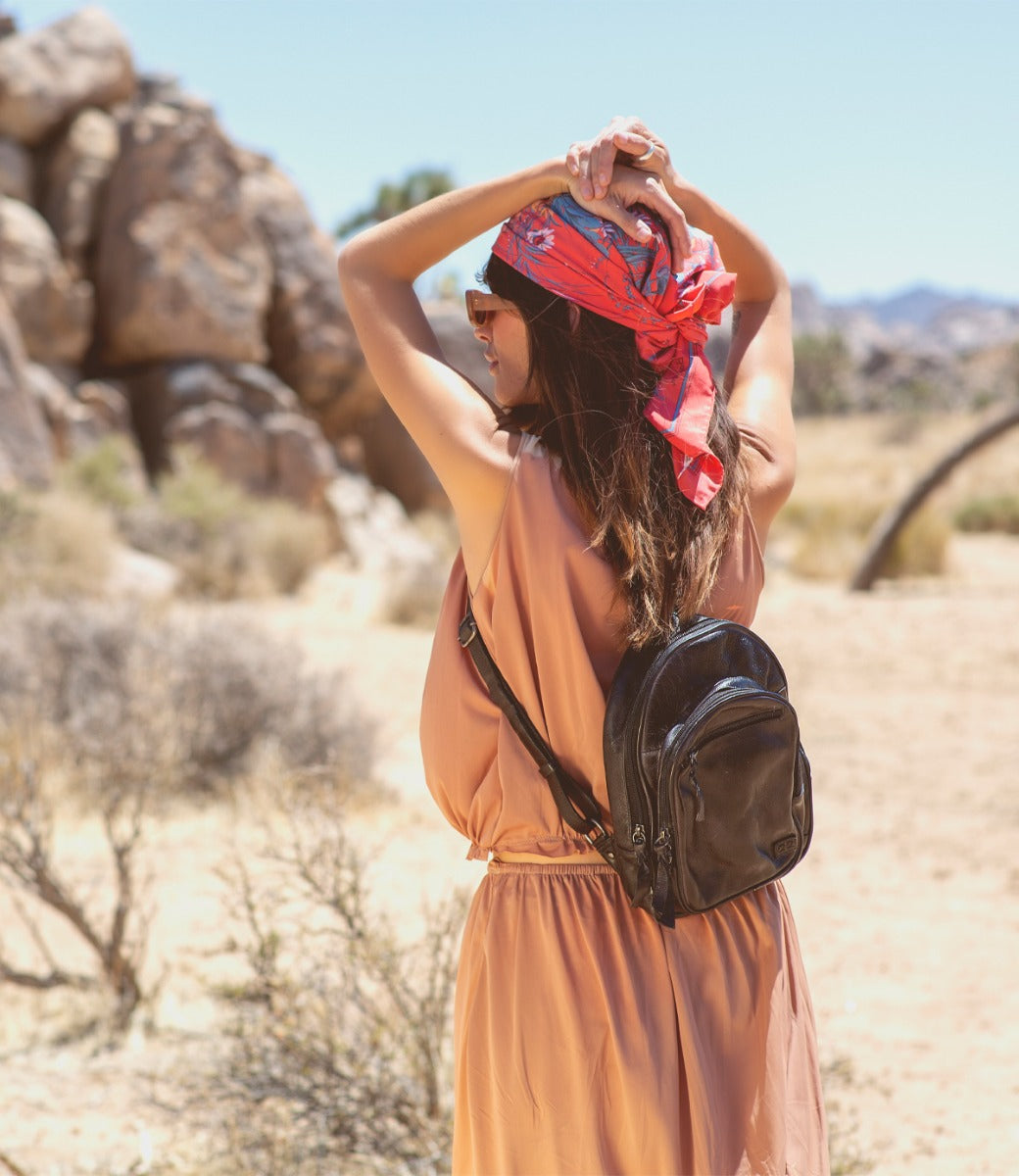 A woman wearing a dress and a Dominique bag by Bed Stu in the desert.