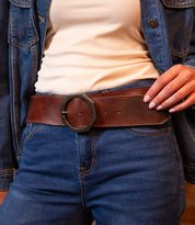 Wearing Bed Stu’s Dreampath belt, a wide genuine leather accessory with a large octagon buckle, paired with a cream ribbed shirt, blue denim jacket, and jeans for rugged durability and style.