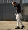 A man wearing a Bed Stu Dreck shirt and white pants.