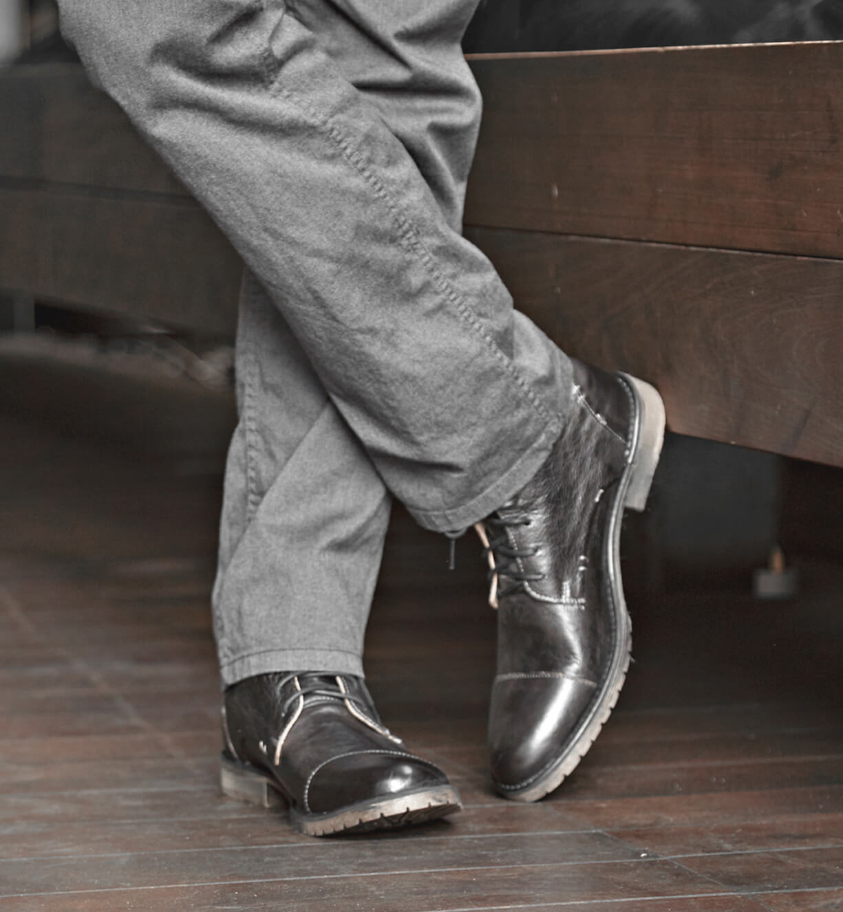 A man wearing a pair of gray Dreck pants and a pair of black Bed Stu shoes.