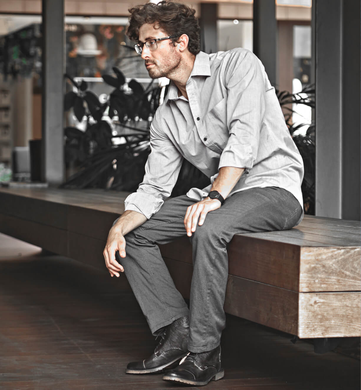 A man sitting on a Bed Stu wooden bench.