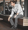 A man sitting on a Bed Stu wooden bench.