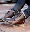 A man wearing a pair of Bed Stu Dreck brown leather boots.