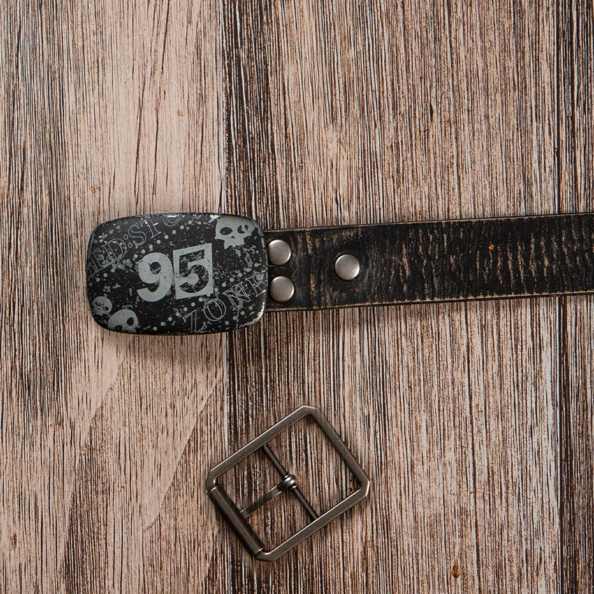 The Bed|Stü Drifter Belt Buckle Bundle features a premium leather belt with skull and "95" details, displayed beside a vintage buckle on wood.