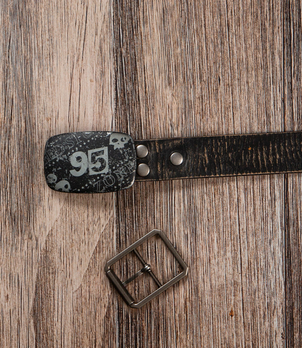 The Bed|Stü Drifter Belt Buckle Bundle features a premium leather belt with skull and "95" details, displayed beside a vintage buckle on wood.