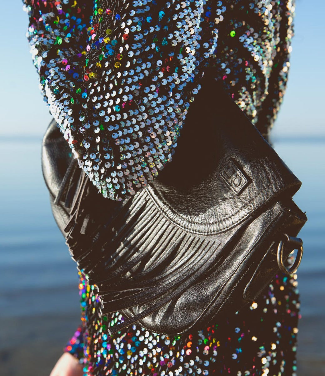 A woman in a sequined dress holding a Bed Stu Eastend purse.