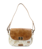 The Bed Stu Elect is a chic tan and cream shoulder bag with a flap closure. It features vintage charm through its metal hardware and a small emblem, while the adjustable shoulder strap adds comfort and versatility.