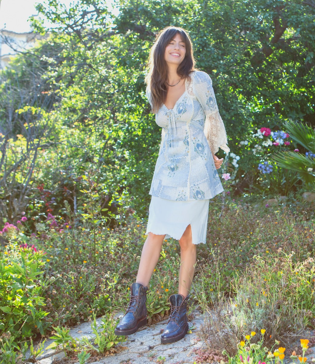 A woman in a floral dress posing in a garden wearing the Elisha II by Bed Stu.