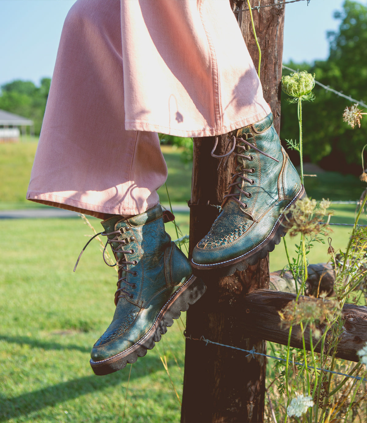 A woman wearing a pair of Bed Stu Elisha II boots on a fence.