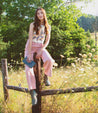 A woman is sitting on a fence in a field wearing Elisha II boots by Bed Stu. 