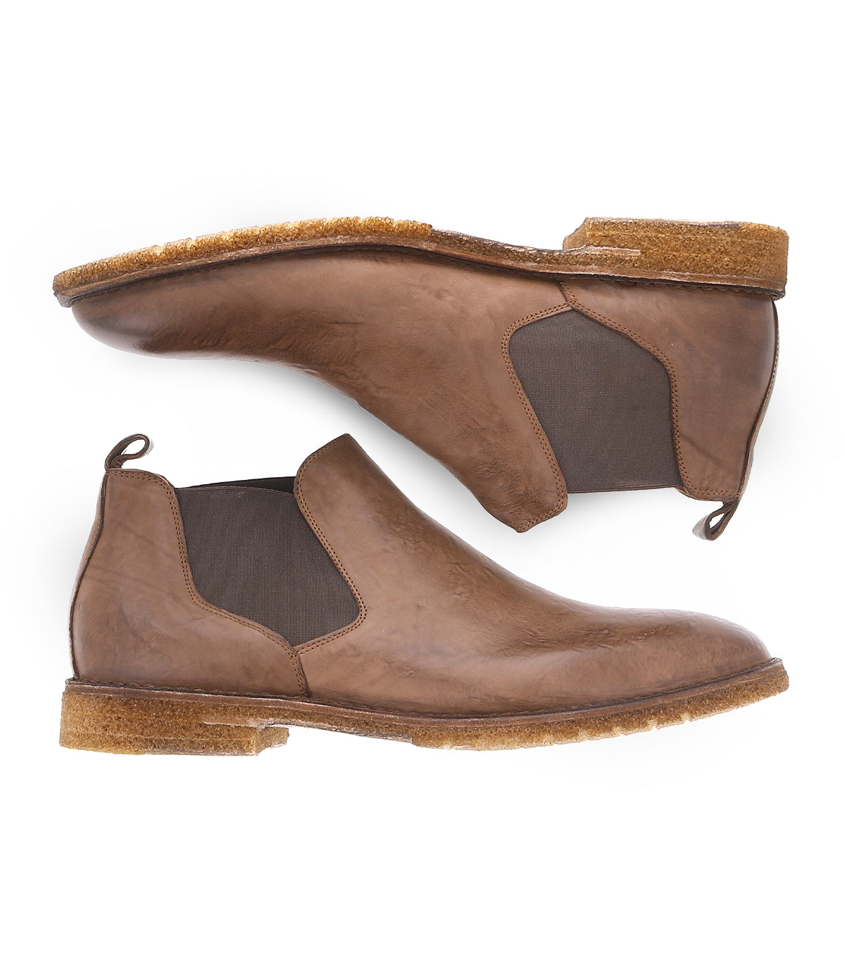 The Elude by Bed Stu are brown leather Chelsea boots with elastic side panels and tan rubber soles, photographed side-by-side, sole to sole. These men's boots showcase a timeless design, expertly handcrafted in Italy for a perfect blend of style and elegance.