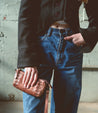 A woman wearing jeans and a jacket holding an Encase purse by Bed Stu.