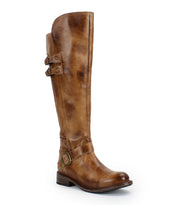 The Bed Stu Essence is a tall, hand-finished leather riding boot featuring two side buckles near the top, one at the ankle, a low stacked heel, and a rounded toe, combining classic equestrian style with modern flair.