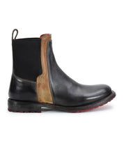 The Bed Stu Ethic is a black Chelsea boot in vegetable-tanned leather with a brown accent panel, black elastic side, and red-tread Vibram sole, shown in profile.