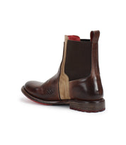 The Bed Stu Ethic is a brown vegetable-tanned leather Chelsea boot featuring a beige side panel, black elastic gusset, red interior lining, and a brown sole, shown from a rear side angle.
