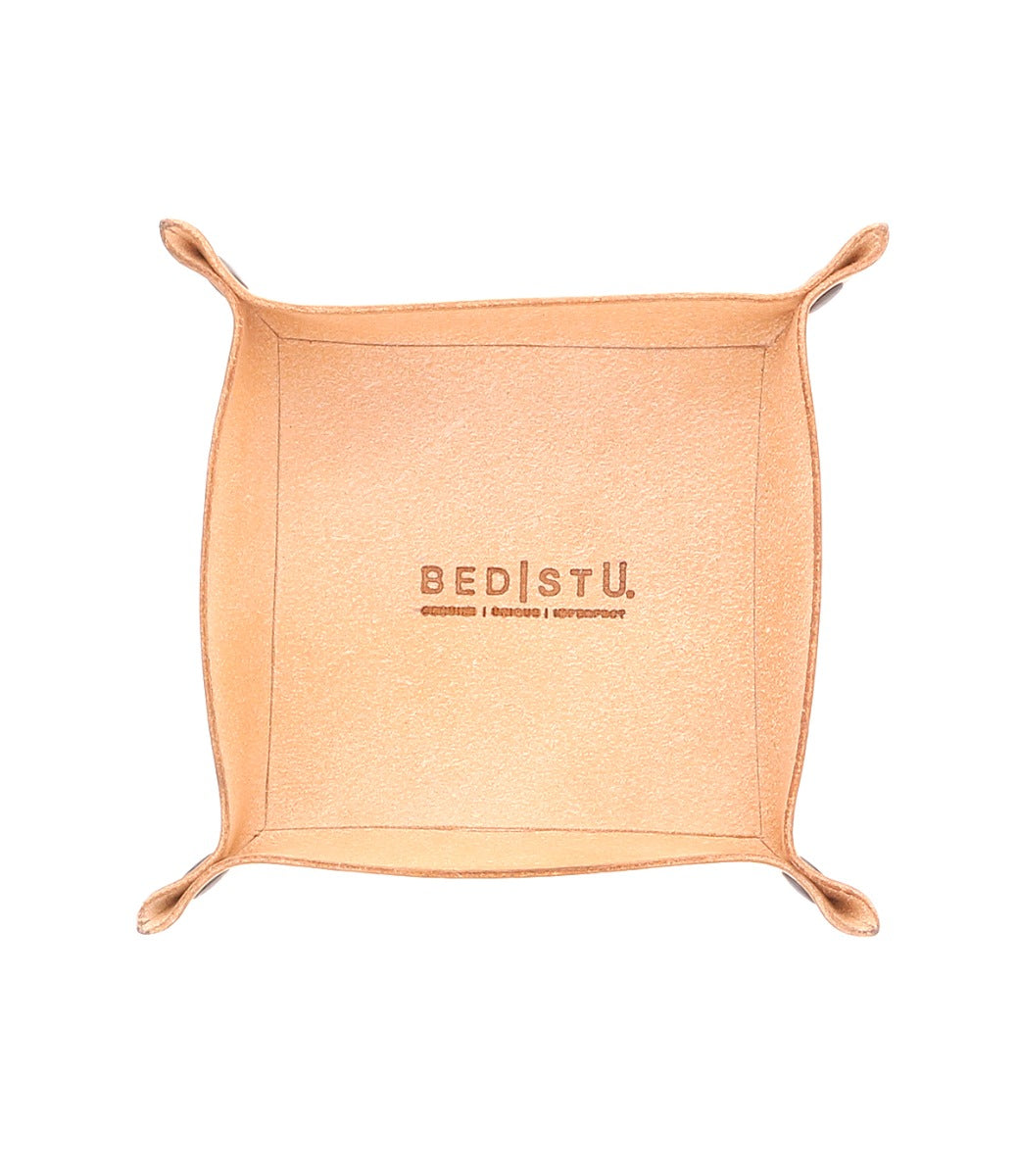 A square, tan leather Expanse Catchall Tray with "Bed Stu" and additional text engraved on the base, perfect for holding keys or loose change, featuring folded corners.