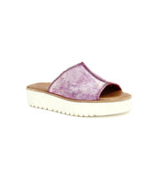 The Bed Stu Fairlee II is a metallic pink flatform leather slide sandal featuring plush cushioning and a white platform sole, shown against a plain white background.