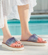 A woman is standing next to a pool wearing Bed Stu Fairlee II sandals.