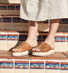 A woman is standing on a set of steps wearing Bed Stu Fairlee II sandals.