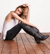 A woman sitting on a wooden floor in Bed Stu Fate boots.