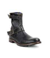The Bed Stu "Fellow" boot features brown leather with two buckled straps and a low heel, offering a moto-inspired edge, shown from the side against a white background.