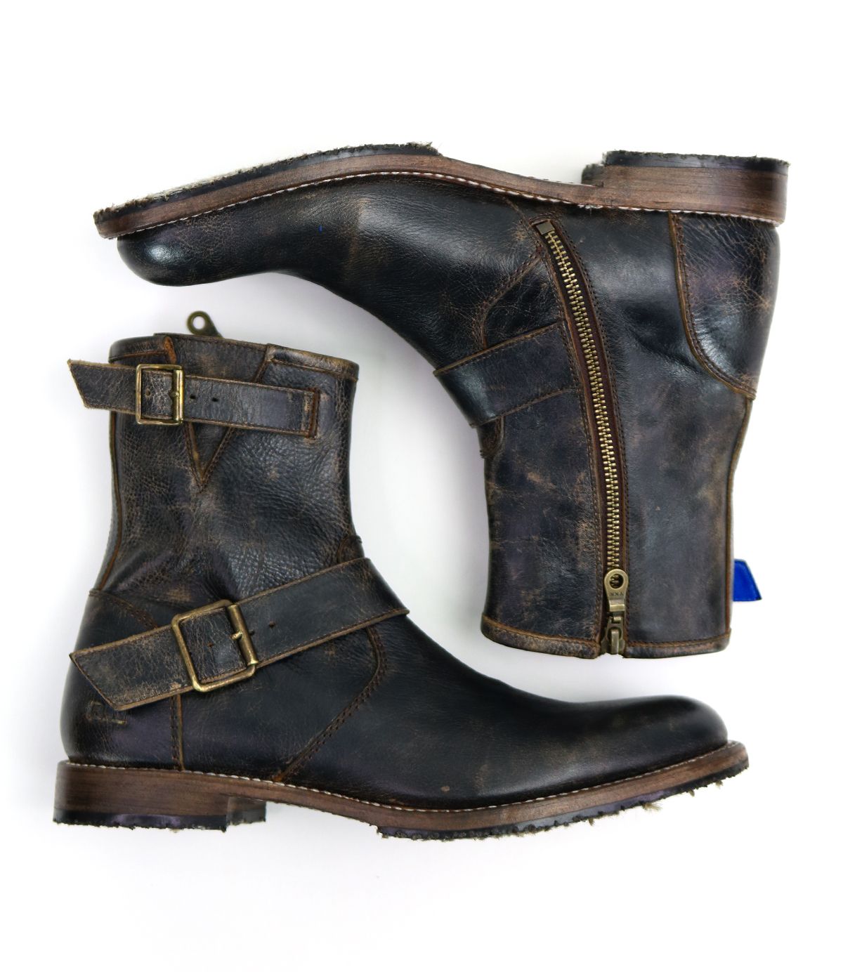 The "Fellow" ankle boots from Bed Stu are crafted from distressed brown leather with a subtle moto-inspired design, featuring side zippers and buckles. These men's leather boots boast Goodyear welt construction for enhanced durability and are elegantly presented from a side and top view on a white background.