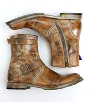 A pair of well-loved leather ankle boots, styled with moto-inspired buckles and zippers from Bed Stu's Fellow collection, displayed on their sides against a white backdrop.