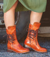 A woman wearing a green dress and a pair of Bed Stu Fen boots.