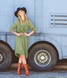 A woman in a green dress standing next to a Bed Stu Fen truck.
