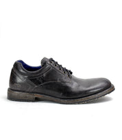 The Bed Stu "Fierce" is a black leather men's derby shoe with laces and a worn-looking sole, combining classic design with modern flair, showcased in side profile against a plain background.