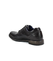 The Bed Stu Fierce men's derby shoe in black leather shows visible wear on the sole from an angled back view, highlighting its classic design with a modern touch.