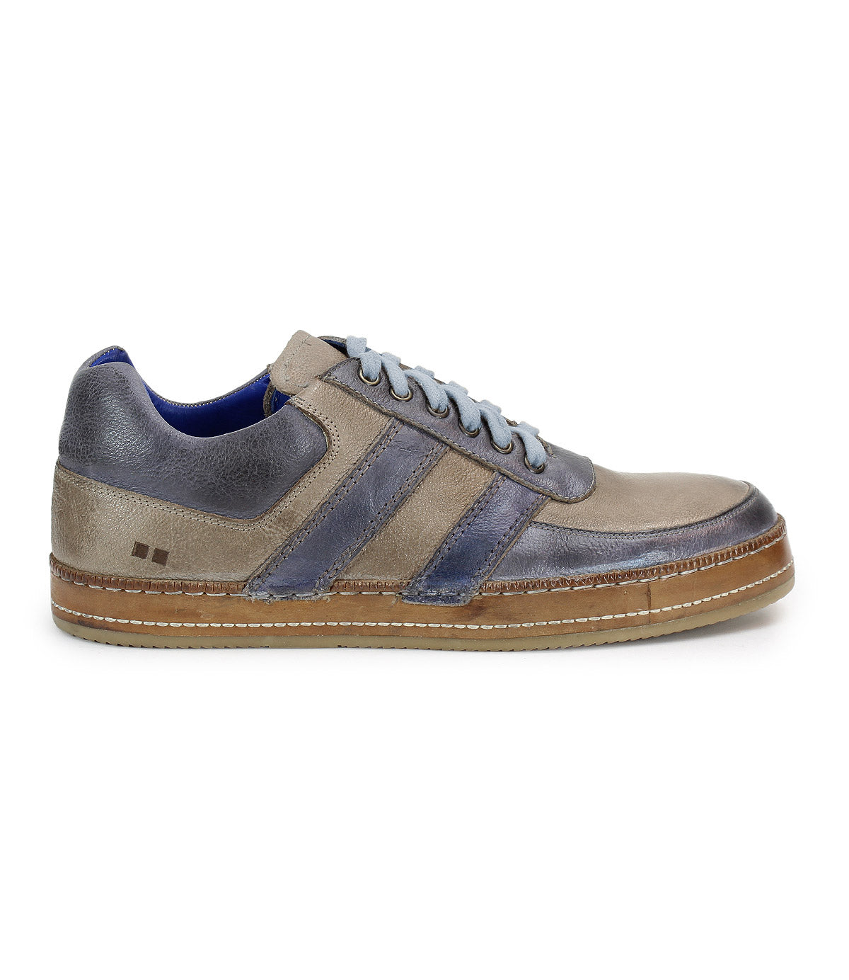 A side view of Bed Stu's Firepower men's sneaker showcases grey and blue suede and leather, white laces, a brown sole, and two dark blue leather stripes, accentuating its sleek vulcanized style.