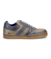 A side view of Bed Stu's Firepower men's sneaker showcases grey and blue suede and leather, white laces, a brown sole, and two dark blue leather stripes, accentuating its sleek vulcanized style.