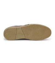 The image showcases the sole of the Bed Stu Firepower men's sneaker, featuring a tan rubber outsole with vertical ridges for traction and subtle leather stripe details.